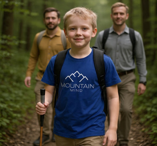 Ein kleiner Junge trägt beim wandern ein blaues Tshirt mit Mountain Mind Logo