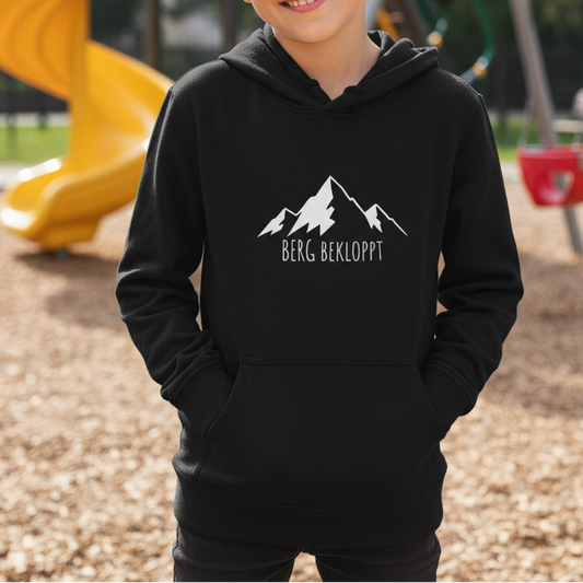 Ein kleine Junge ist auf einem Spielplatz und trägt einen Hoodie mit Berg Bekloppt Motiv
